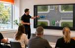 Fahrlehrer erklärt Vorfahrtsregeln an einem wandmontierten Kindermann Touch-Display im Theorieraum
